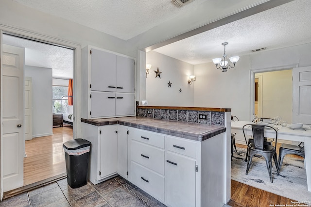 kitchen featuring white cabinets, a textured ceiling, and tile floors