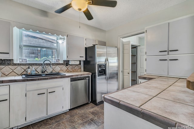 kitchen with sink, appliances with stainless steel finishes, tasteful backsplash, and tile countertops