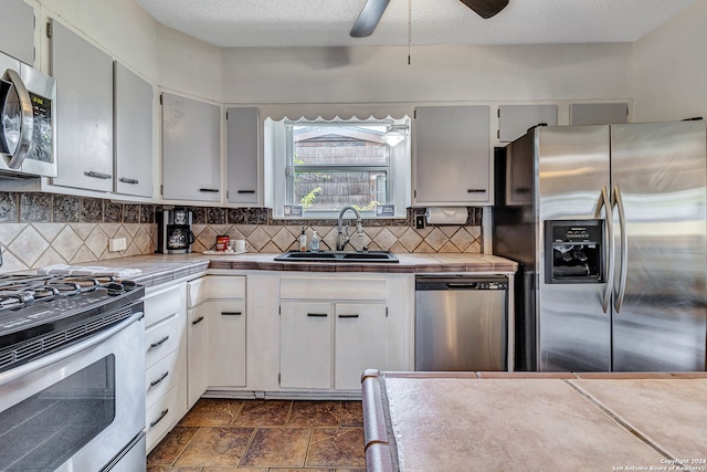 kitchen featuring sink, ceiling fan, stainless steel appliances, and tile countertops