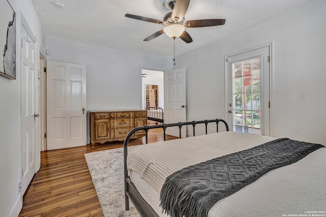 bedroom featuring hardwood / wood-style floors, ceiling fan, access to exterior, and a textured ceiling