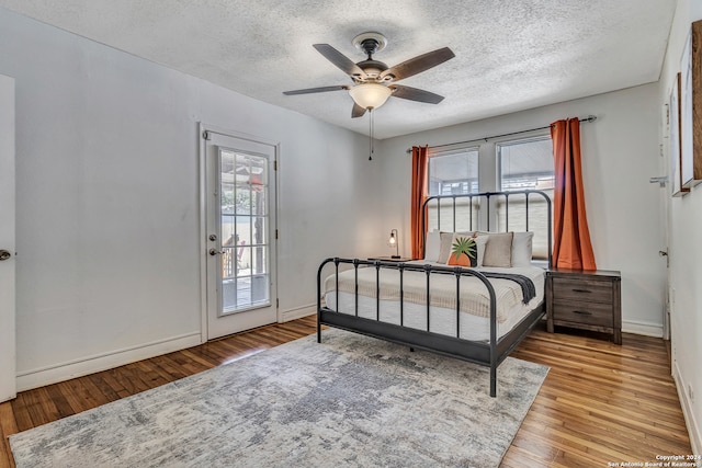 bedroom with wood-type flooring, a textured ceiling, ceiling fan, and access to exterior