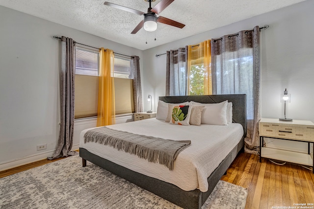 bedroom with ceiling fan, hardwood / wood-style flooring, and a textured ceiling