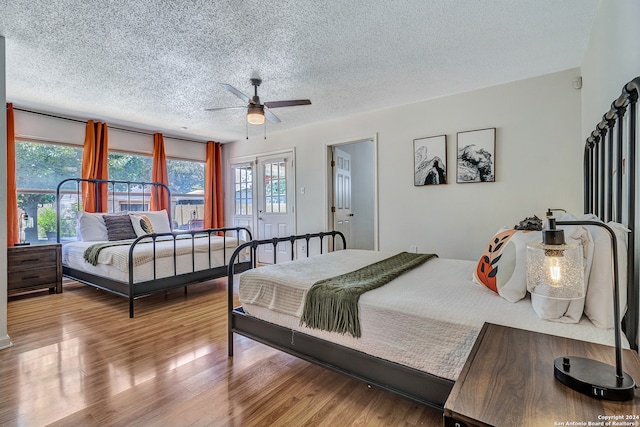 bedroom with hardwood / wood-style flooring, ceiling fan, and a textured ceiling