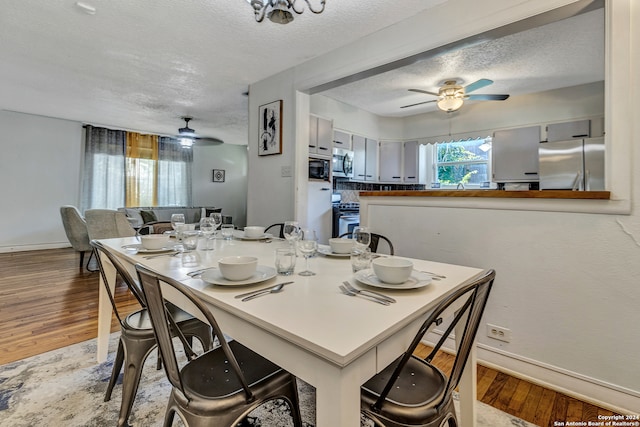 dining area with a textured ceiling, ceiling fan, and light wood-type flooring