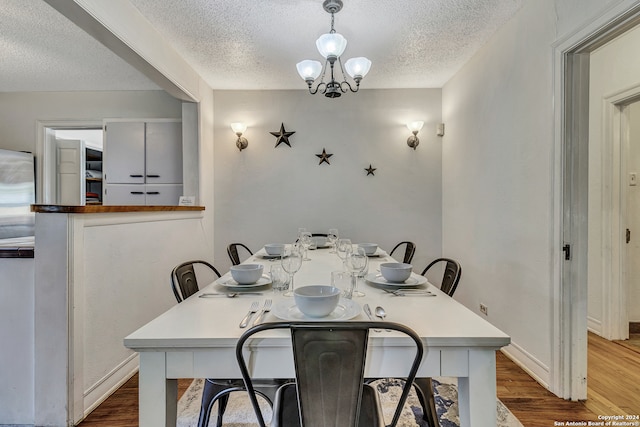 dining area with a textured ceiling, hardwood / wood-style flooring, and a chandelier