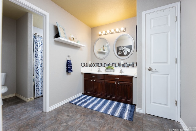 bathroom featuring vanity, backsplash, and toilet