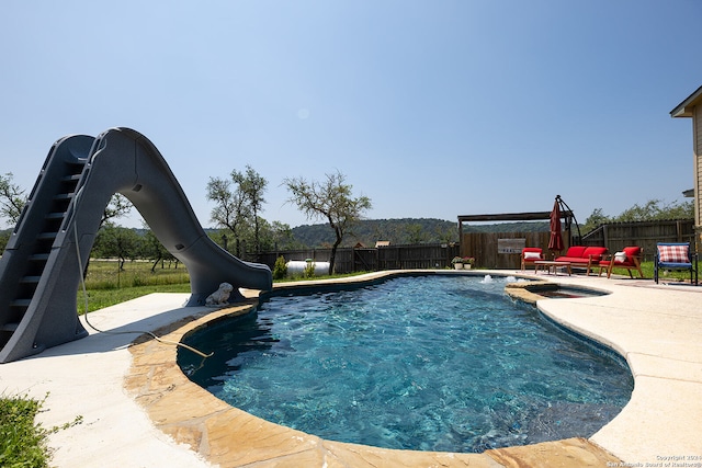 view of pool with pool water feature, a water slide, and a patio