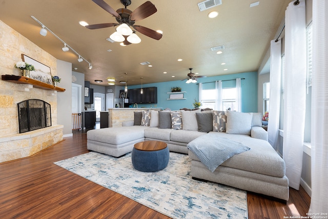 living room featuring dark hardwood / wood-style floors, track lighting, and a fireplace