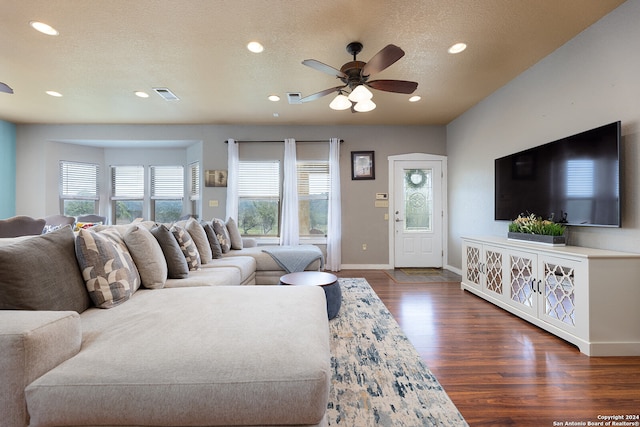 living room with ceiling fan, dark wood-type flooring, and a textured ceiling