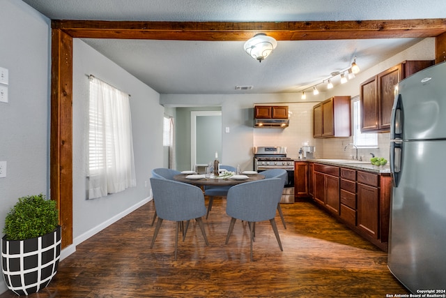 kitchen with rail lighting, appliances with stainless steel finishes, dark hardwood / wood-style flooring, and range hood