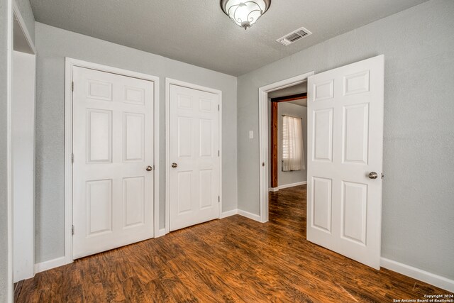 unfurnished bedroom with dark wood-type flooring and a textured ceiling