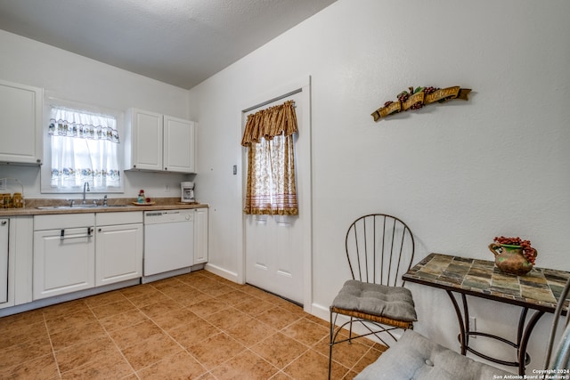 kitchen featuring sink, dishwasher, light tile floors, and white cabinetry