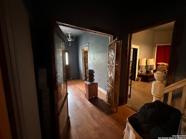 hallway featuring wood-type flooring and an inviting chandelier