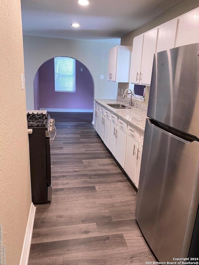 kitchen featuring sink, stainless steel refrigerator, white cabinetry, dark wood-type flooring, and range with gas stovetop