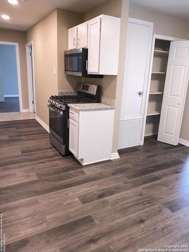 kitchen with white cabinets, light stone counters, stainless steel appliances, and dark hardwood / wood-style floors