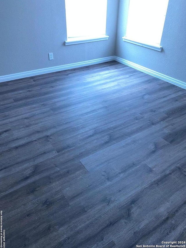 unfurnished room with plenty of natural light and dark wood-type flooring