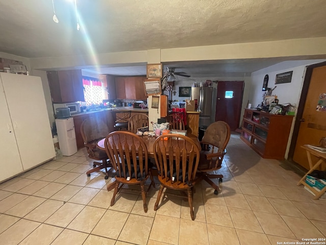 dining room with a textured ceiling, ceiling fan, and light tile flooring