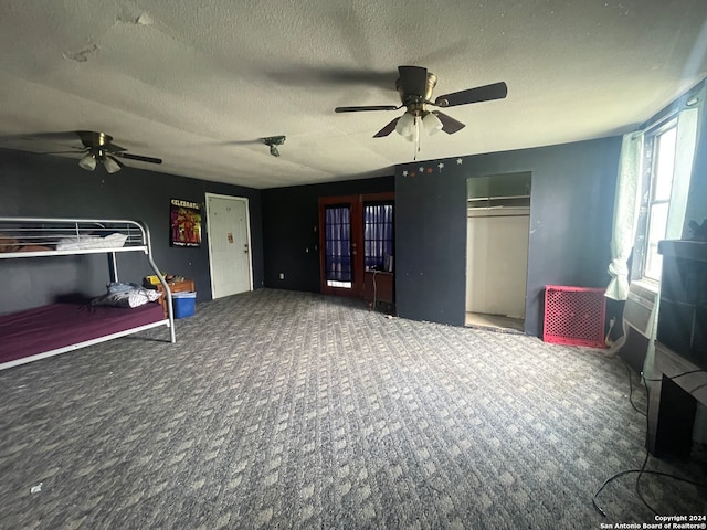 bedroom with a closet, ceiling fan, carpet flooring, and a textured ceiling