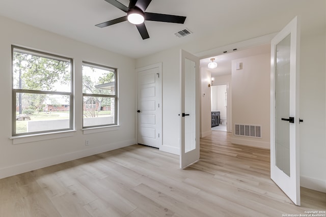 unfurnished room with ceiling fan, a healthy amount of sunlight, light wood-type flooring, and french doors