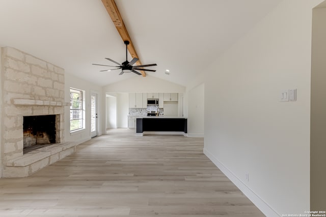 unfurnished living room with beamed ceiling, ceiling fan, a fireplace, and light wood-type flooring