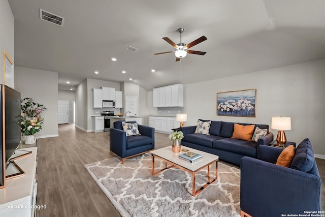 living room featuring ceiling fan, vaulted ceiling, sink, and light hardwood / wood-style flooring