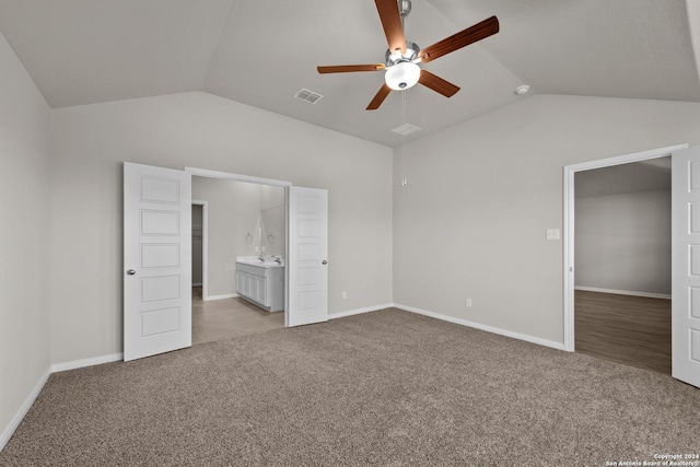 unfurnished bedroom with light carpet, ceiling fan, vaulted ceiling, and connected bathroom