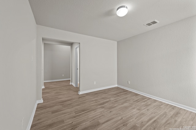 empty room with a textured ceiling and light wood-type flooring