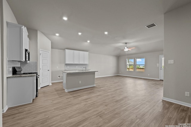 kitchen with electric stove, light hardwood / wood-style floors, sink, an island with sink, and white cabinets