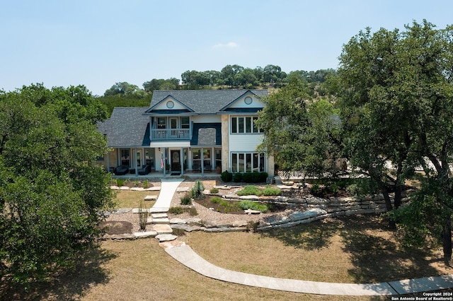 rear view of property with a porch and a balcony