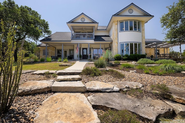 back of property with ceiling fan, a balcony, and a porch