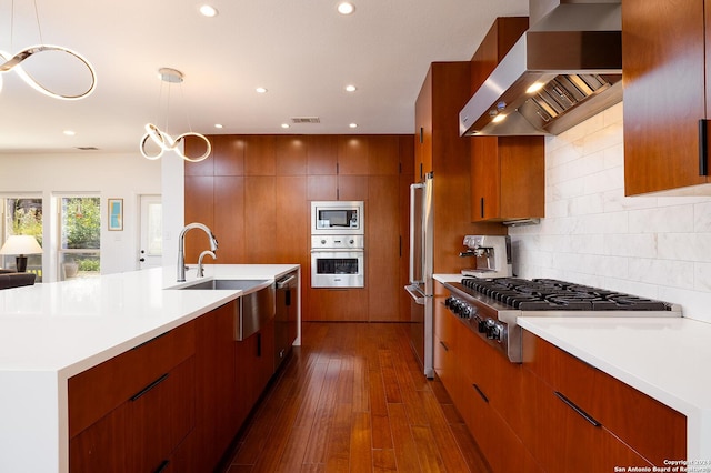 kitchen featuring wall chimney exhaust hood, stainless steel appliances, dark hardwood / wood-style flooring, backsplash, and decorative light fixtures