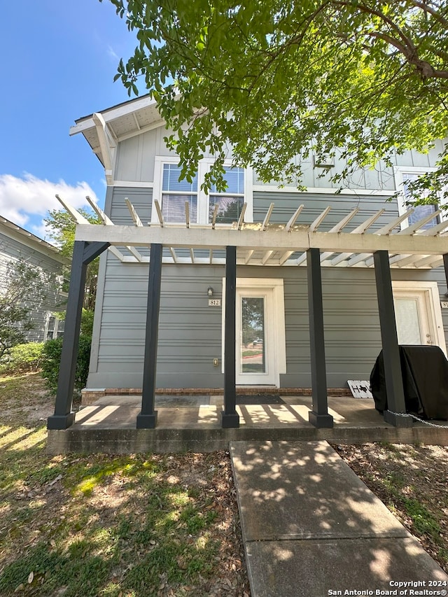 back of property with a pergola and a patio area