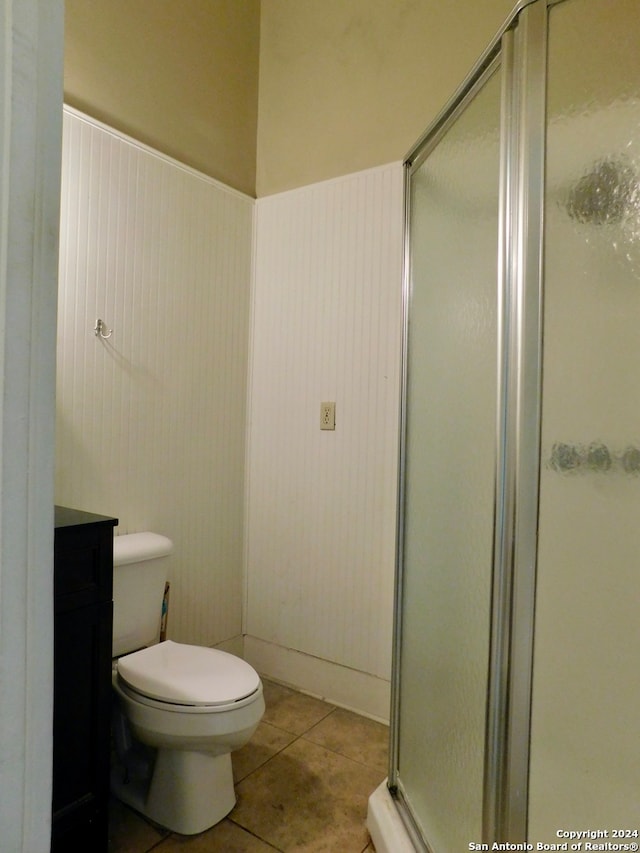 bathroom featuring a shower with shower door, tile flooring, vanity, and toilet