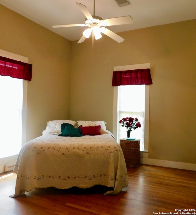 bedroom featuring ceiling fan, multiple windows, and hardwood / wood-style flooring