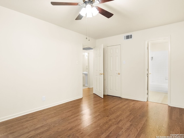 unfurnished bedroom with hardwood / wood-style flooring, a closet, ensuite bathroom, and ceiling fan