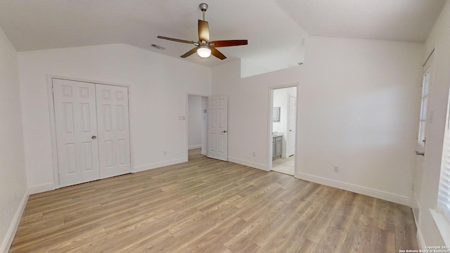 unfurnished bedroom featuring connected bathroom, lofted ceiling, light wood-type flooring, and ceiling fan