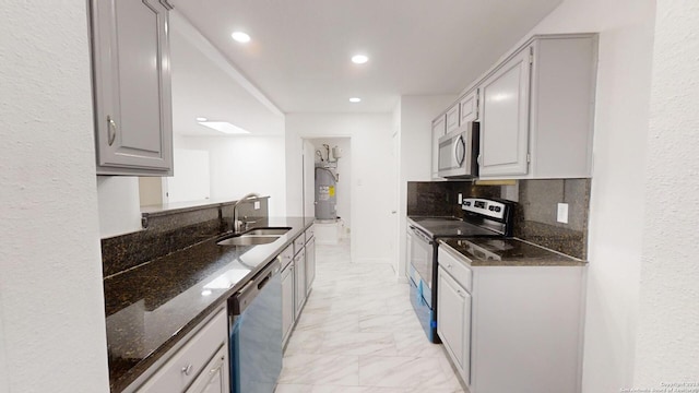 kitchen featuring appliances with stainless steel finishes, dark stone counters, backsplash, sink, and light tile floors