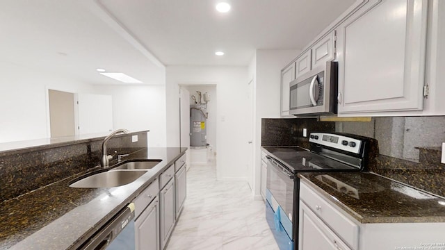 kitchen with dark stone countertops, stainless steel appliances, sink, tasteful backsplash, and light tile flooring