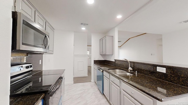 kitchen with dark stone counters, gray cabinets, light tile floors, sink, and appliances with stainless steel finishes