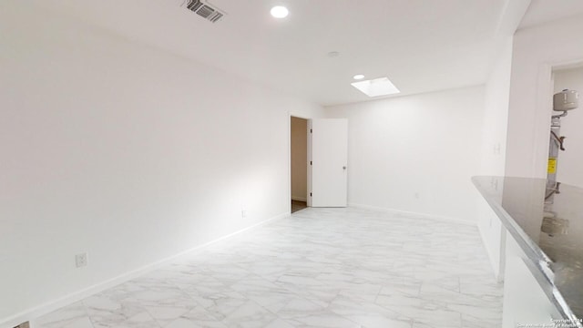 unfurnished room featuring light tile floors and a skylight