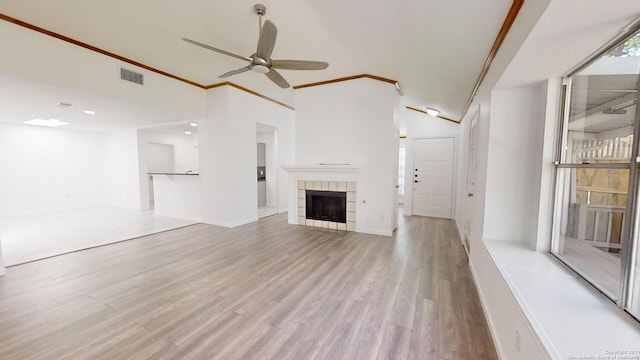 unfurnished living room with lofted ceiling, a fireplace, ornamental molding, hardwood / wood-style flooring, and ceiling fan