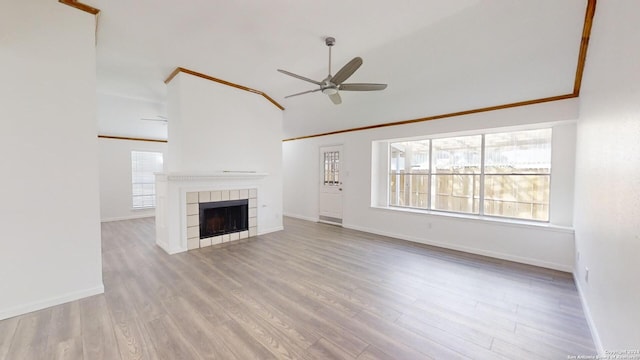 unfurnished living room featuring ceiling fan, a healthy amount of sunlight, hardwood / wood-style flooring, and a tile fireplace