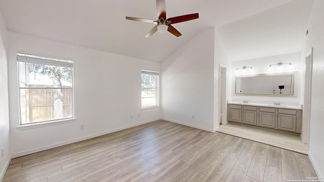 unfurnished bedroom featuring light hardwood / wood-style floors, ceiling fan, multiple windows, and ensuite bath