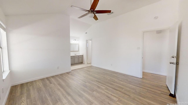 empty room with high vaulted ceiling, ceiling fan, a wealth of natural light, and light hardwood / wood-style floors