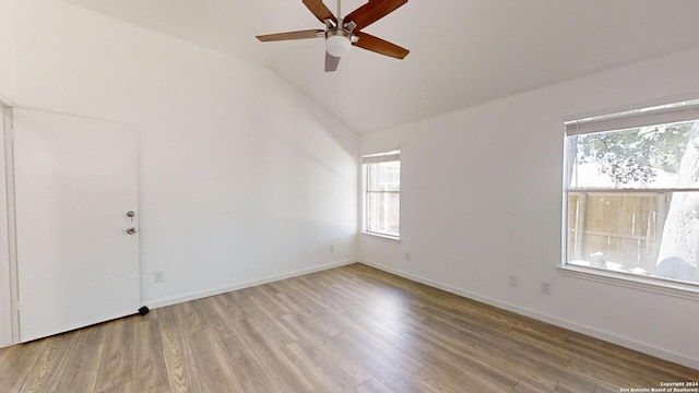 unfurnished room with a healthy amount of sunlight, hardwood / wood-style floors, and lofted ceiling