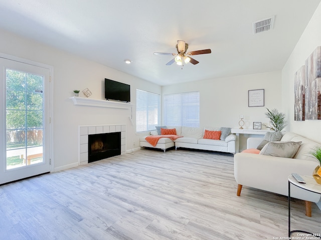 living room featuring light hardwood / wood-style floors, a fireplace, and ceiling fan