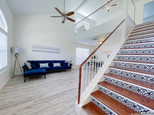 staircase with plenty of natural light, high vaulted ceiling, and light hardwood / wood-style floors