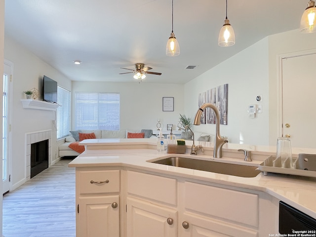 kitchen featuring light hardwood / wood-style floors, hanging light fixtures, a fireplace, sink, and ceiling fan