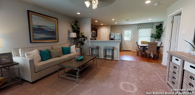 carpeted living room with ceiling fan