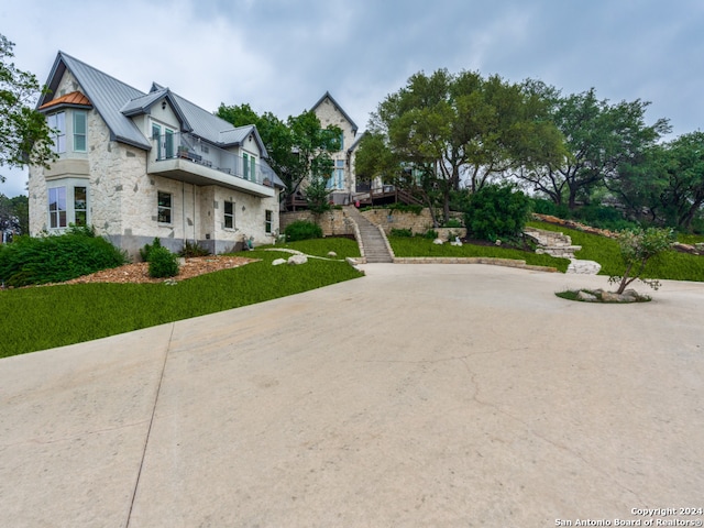 view of front of home featuring a balcony and a front yard